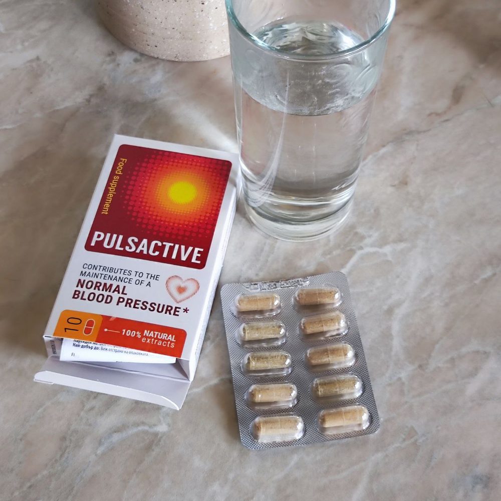Отворена кутия Pulsactive и блистер с капсули до чаша вода